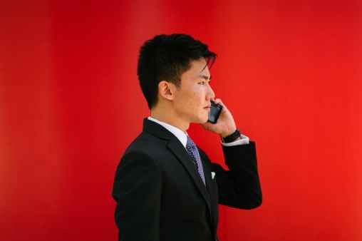 man holding smartphone wearing black notched lapel suit jacket